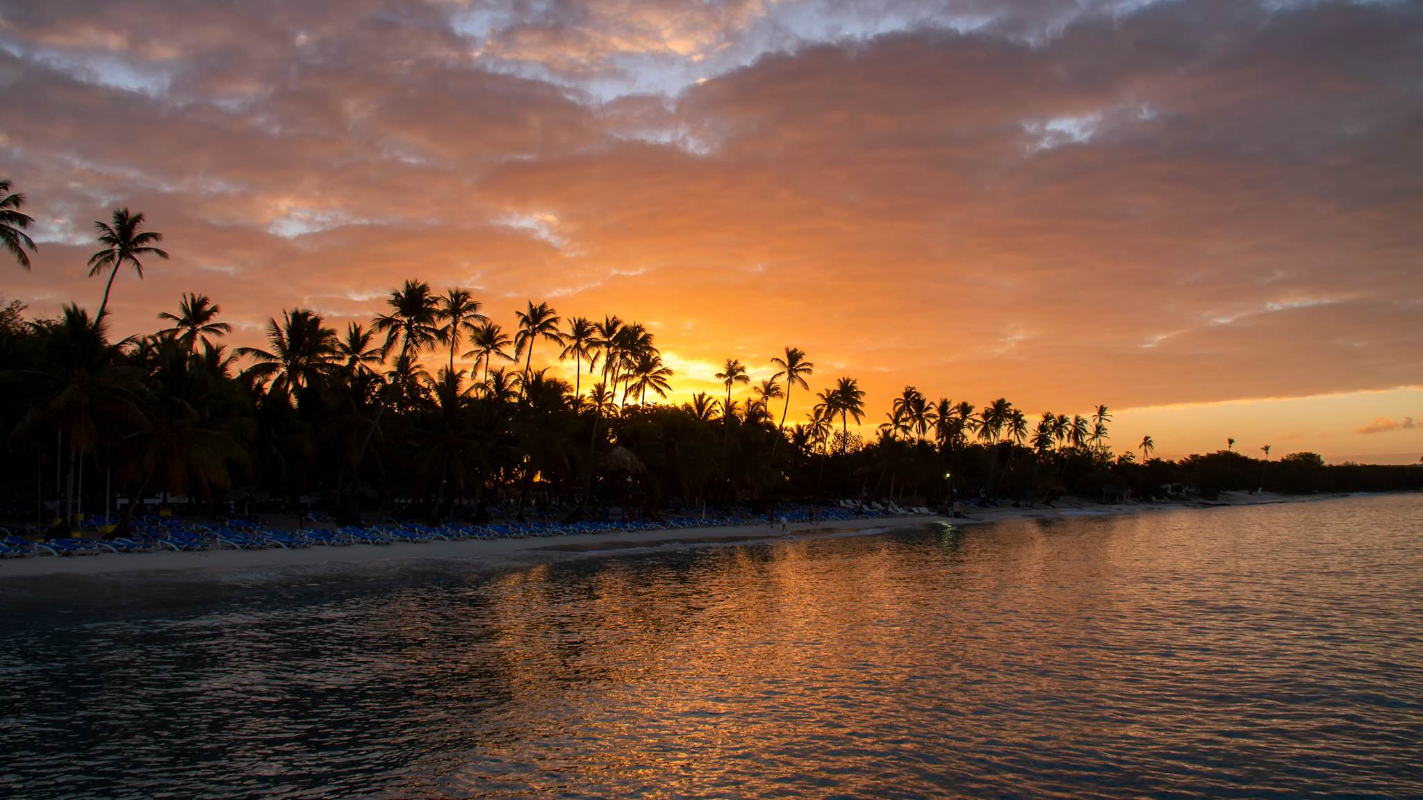 Ein weiter Strand mit Palmen bei Sonnenuntergang